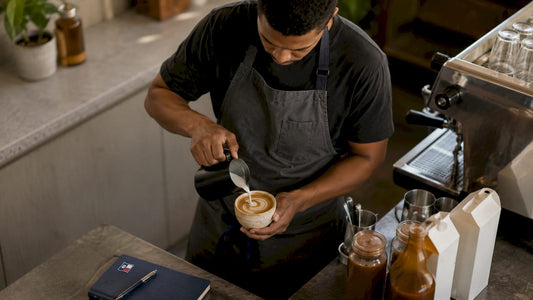 Barista pouring vegan milk into salted caramel coffee cup