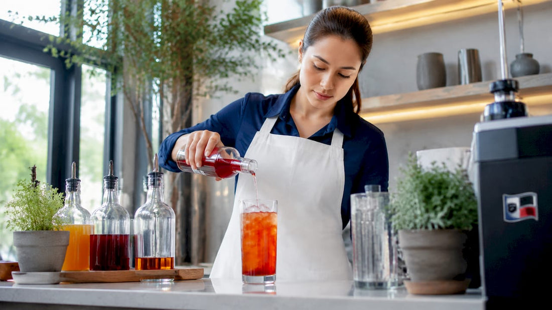 Barista pouring fruit syrup into iced tea glass