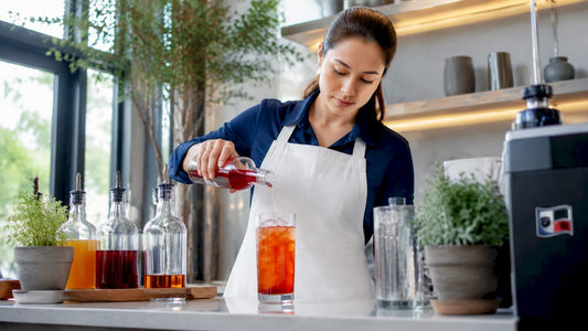 Barista pouring fruit syrup into iced tea glass