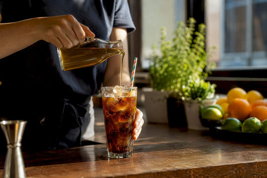 Hands pouring syrup into glass of dirty soda