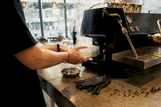 Hands rinsing espresso machine with descaling