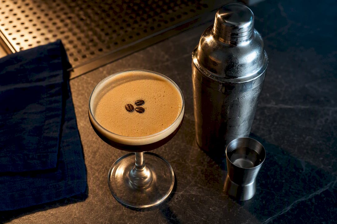 Foamy espresso martini mocktail beside shaker