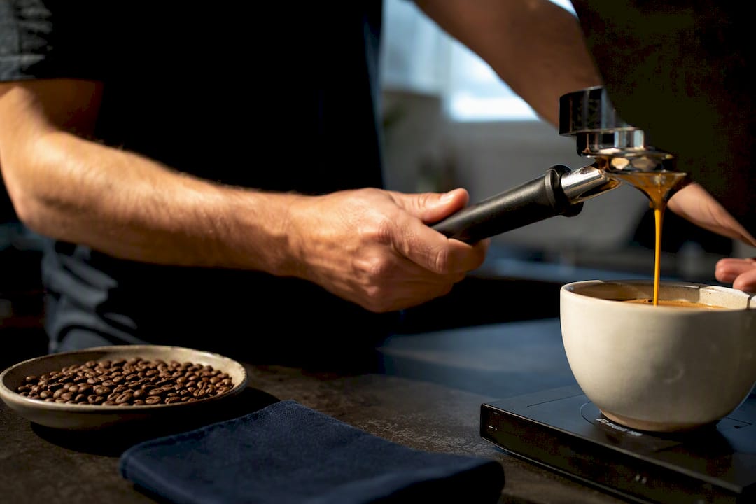 Espresso extraction beside roasted coffee beans